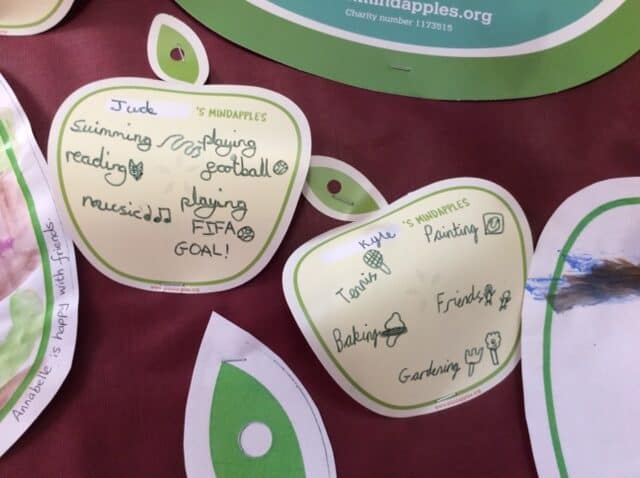 Close up of apple shaped applecards with children's 5 a day for their mind including swimming, music, friends and playing football.