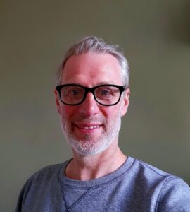 Man with wearing grey t shirt and black glasses
