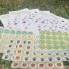 Sheets of multi-coloured head shaped stickers and large posters displaying images of suggestions of 50 ways to take care of your mind lying on a grass background.