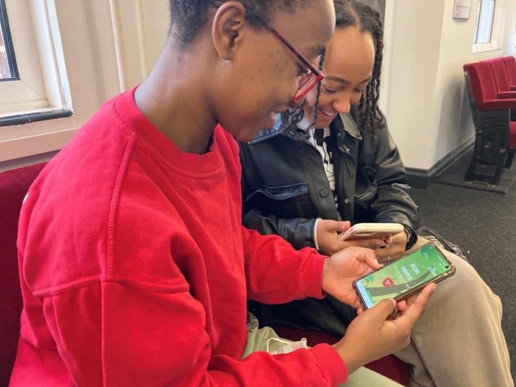 two students smile as they operate the an app on their mobile phones